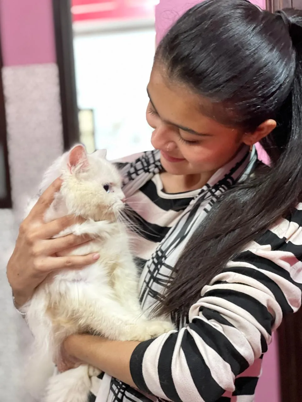 A young woman holding her fluffy white Persian kitten
