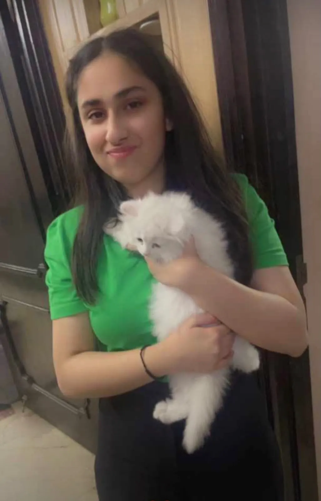 A young woman holding her fluffy white Persian kitten at home