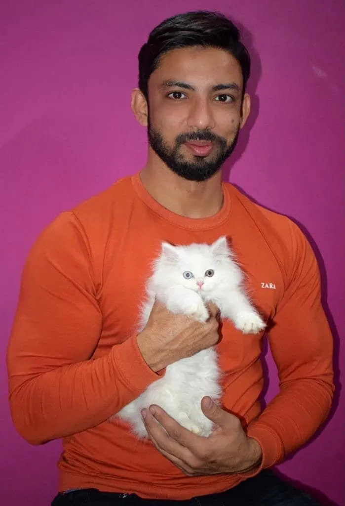The owner of The Pet Zone holding a fluffy white Persian kitten with blue and green eyes