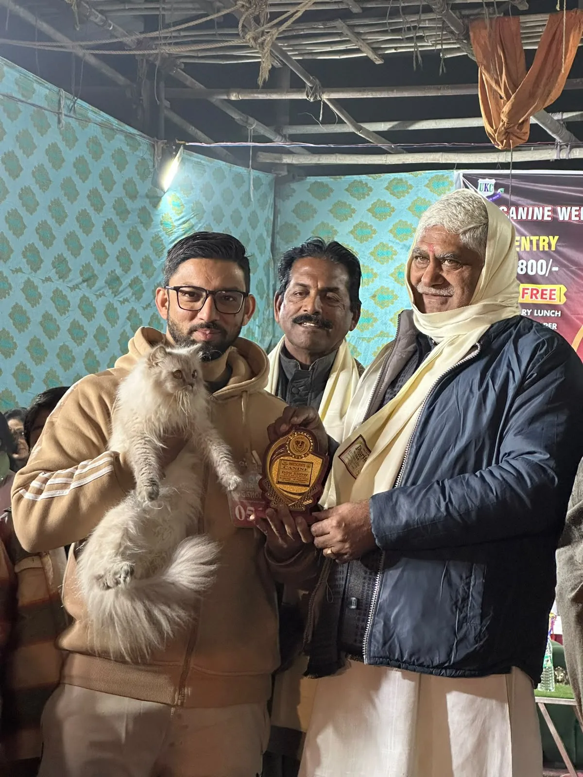 Owner receiving a show award while holding a cream Persian cat